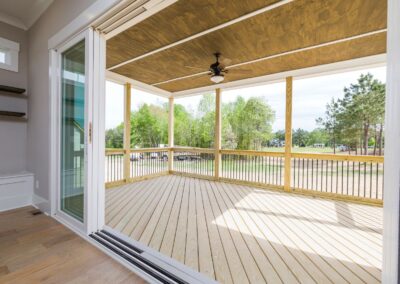 New covered patio addition with ceiling fan and wood deck overlooking backyard trees.