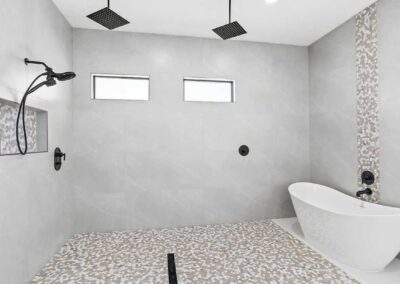 Luxury walk-in shower with dual rain shower heads and a freestanding tub in a Vero Beach custom home.