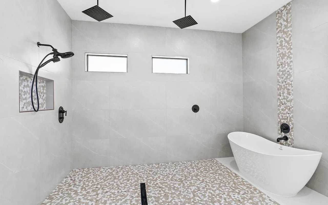 Luxury walk-in shower with dual rain shower heads and a freestanding tub in a Vero Beach custom home.