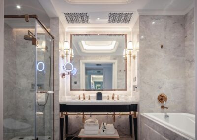 Elegant bathroom remodel with marble walls, glass shower, and gold fixtures in Vero Beach