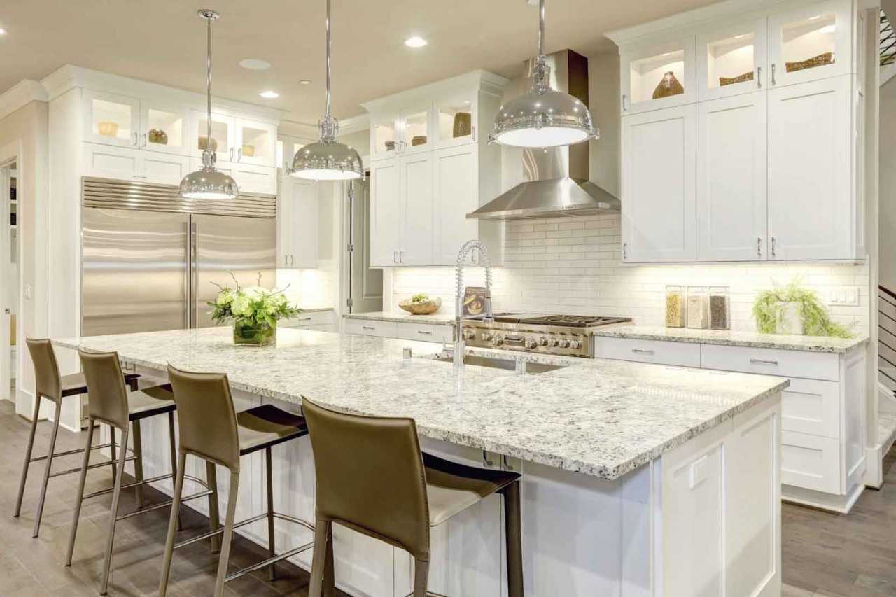 Luxury white kitchen remodel with large granite island and pendant lighting in Vero Beach