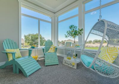Cozy sunroom addition with aqua chairs, hanging swing, and large windows for natural light.