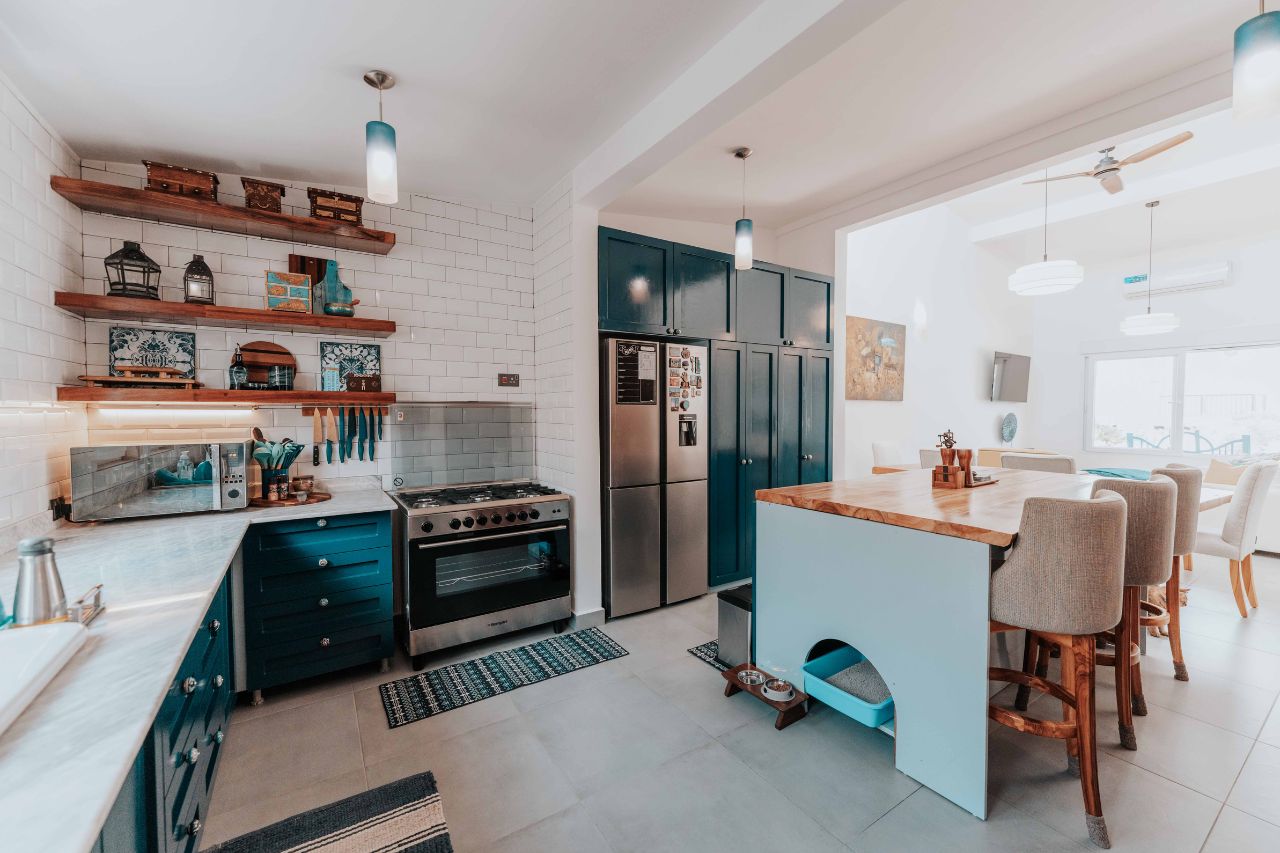 Modern kitchen remodel with blue cabinets, wood island, and stainless steel appliances.